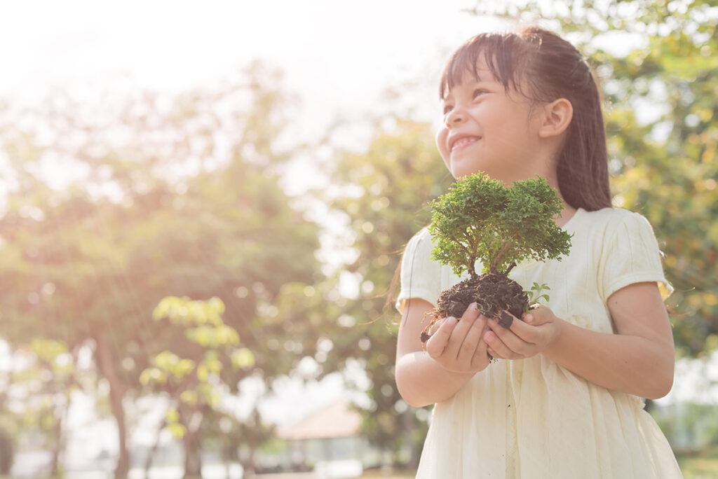 A young girl holding green plant