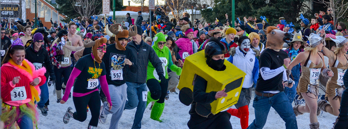 Participants running in winter during a holiday fun run fundraiser, part of a themed charity race.