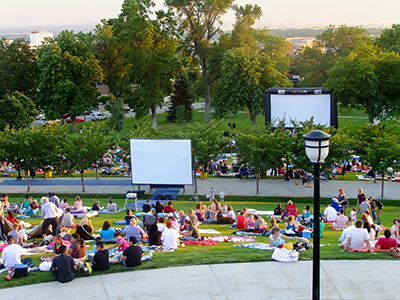 Families sitting in a park watching a film, which is an example of a fundraising idea for kids.
