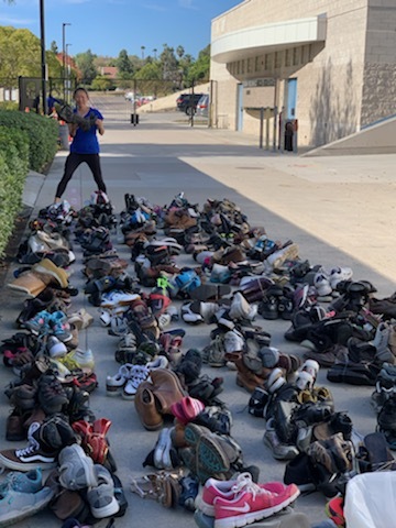 Woman standing in front of large pile of shoes