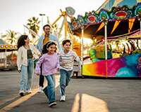 Colorful community carnival with games, booths, and families gathering to support adoption fundraising through local events.