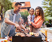  Grill sizzling at a cookout fundraiser with families gathered to enjoy food and fun while raising money to support adoption.