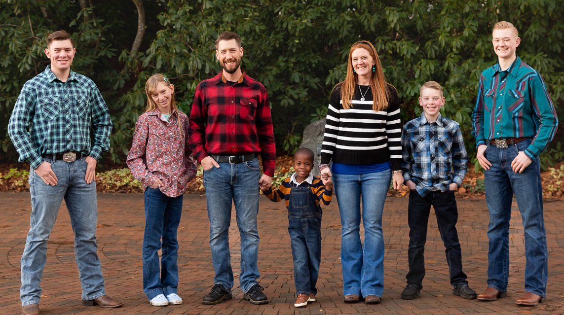The LeMay Family is pictured standing together holding hands.