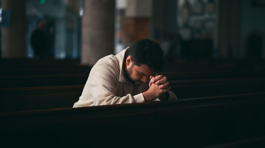 Christian man praying for guidance and blessing during church worship.