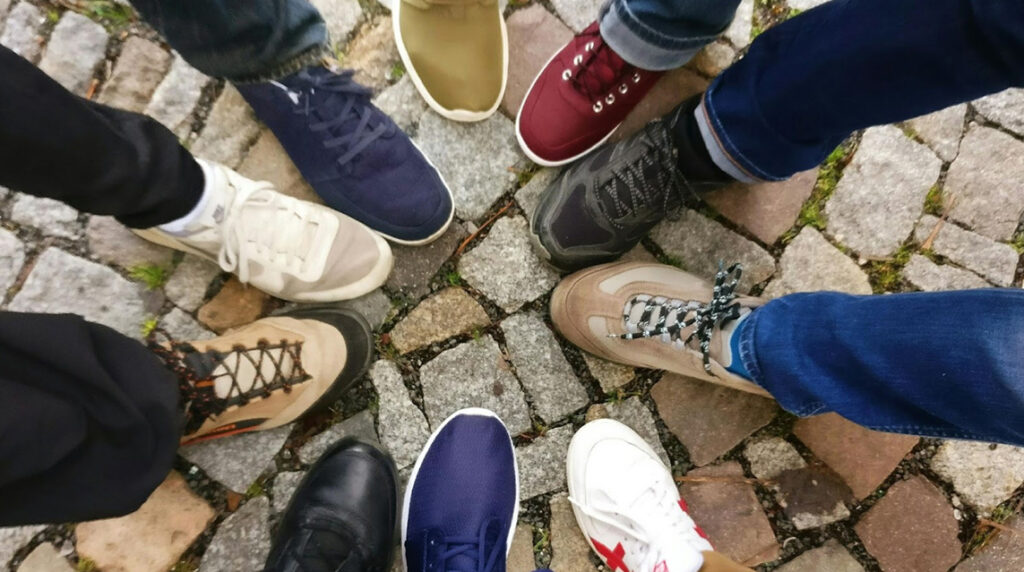 Ten people standing with their shoes forming a circle.