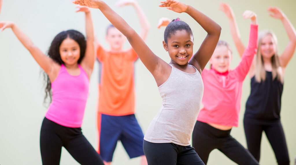 A children’s dance team practices together and smiles.