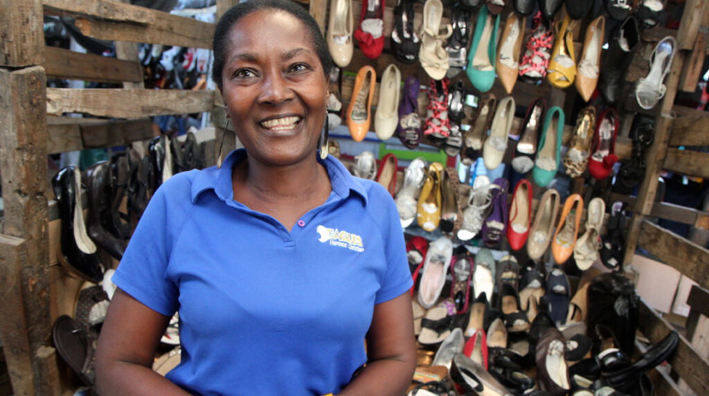 A micro-entrepreneur proudly stands in her shoe store.