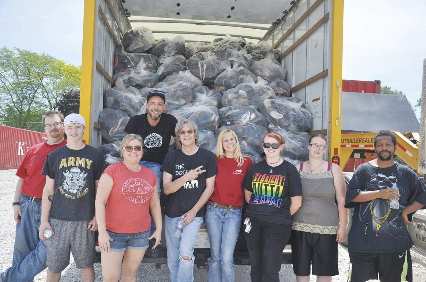 A group from Dog Gone Rescue stand and pose in front of all the shoes they collected during their animal shelter fundraiser