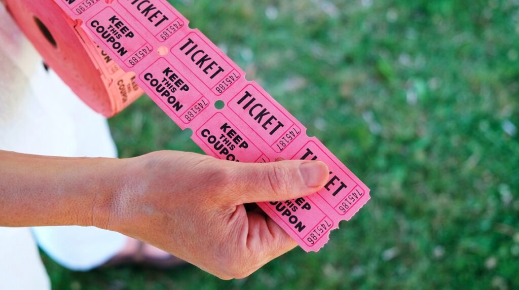 A person holding a roll of raffle tickets as part of fundraising efforts.