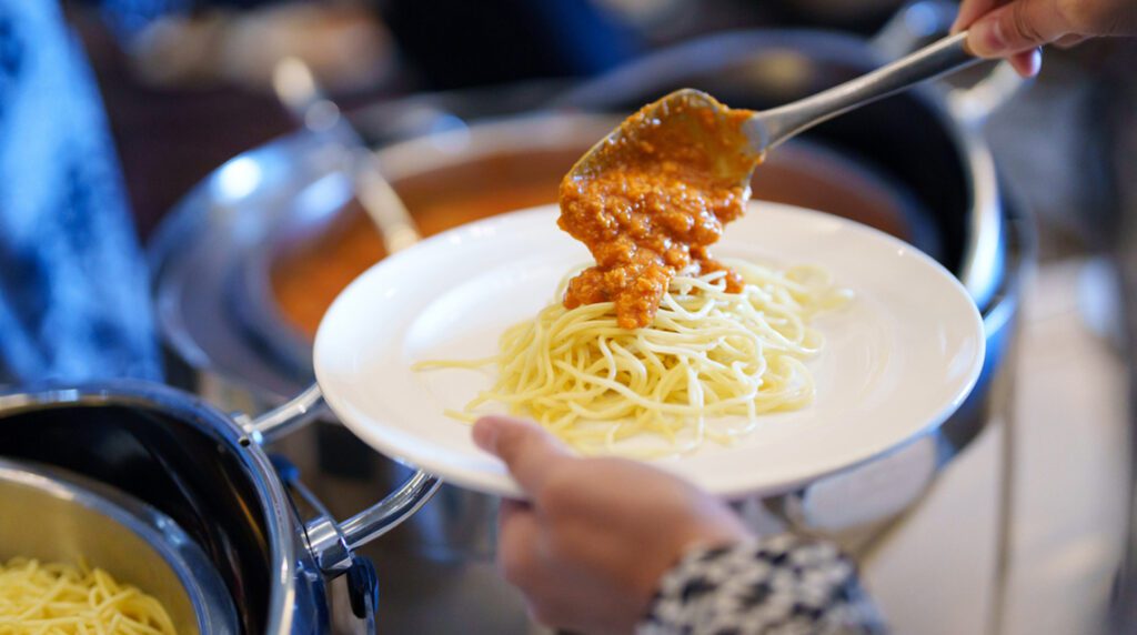 A person is preparing a plate of spaghetti at a spaghetti dinner fundraiser.